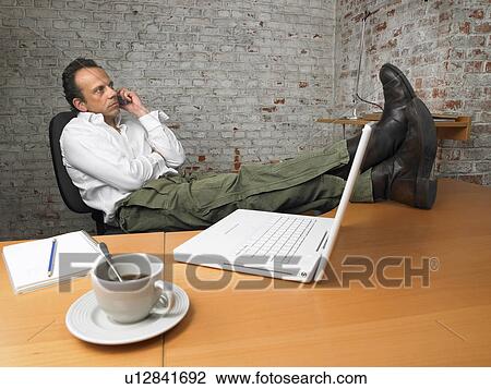 Businessman on the phone, feet on desk., Brussels, Belgium. View Large Photo Image Stock Image - Businessman on the phone, feet on desk., Brussels, Belgium.. Fotosearch