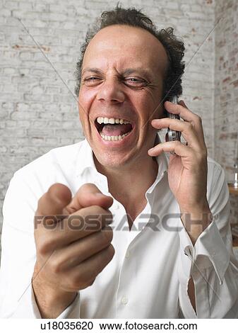 Stock Image - Businessman on the phone pointing at camera and laughing., Brussels, Belgium.. Fotosearch
