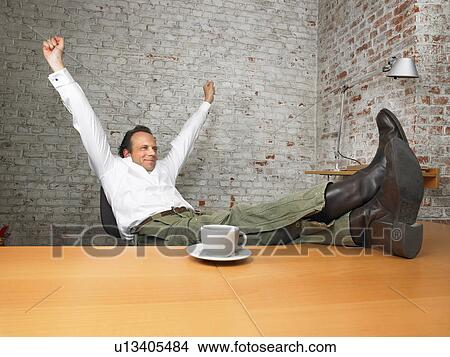 Businessman stretching with feet on desk., Brussels, Belgium. View Large Photo Image Picture - Businessman stretching with feet on desk., Brussels, Belgium.. Fotosearch