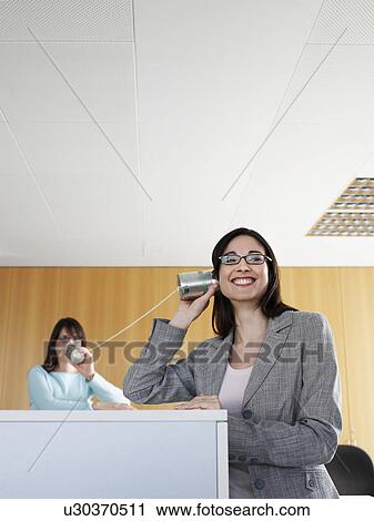Businesswoman using tin can to communicate with colleague, smiling View Large Photo Image Stock Image - Businesswoman using tin can to communicate with colleague, smiling. Fotosearch