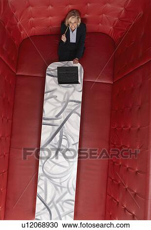 Stock Image - Businesswoman working at a table with red seating. Fotosearch
