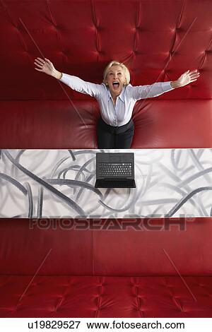Stock Photo - Businesswoman working at a table with red seating. Fotosearch