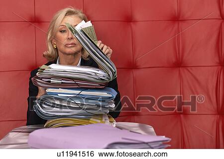 Stock Photograph - Businesswoman working at a table with red seating. Fotosearch