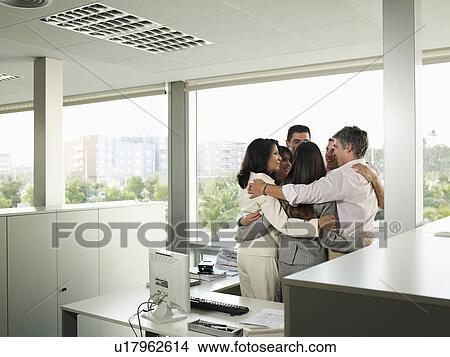 Picture - Group of colleagues embracing in office. Fotosearch