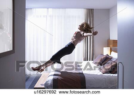 Woman jumping onto bed View Large Photo Image Stock Image - Woman jumping onto bed. Fotosearch