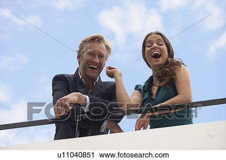 Stock Image - Young businessman and business woman on balcony.. Fotosearch