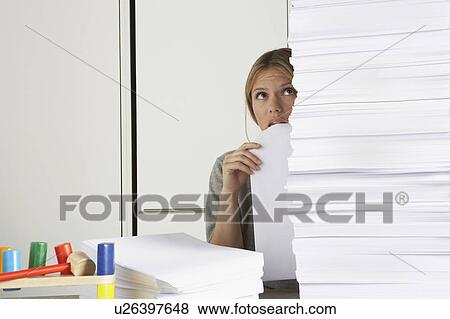 Young woman working from home with huge pile of paper. View Large Photo Image Stock Photo - Young woman working from home with huge pile of paper.. Fotosearch