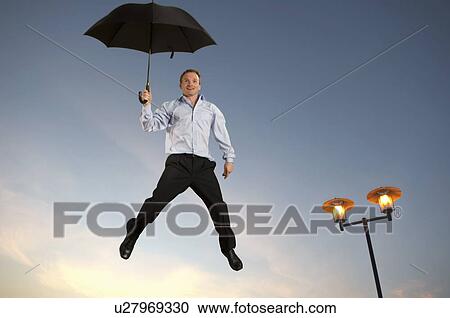 Stock Image - Businessman floating with an umbrella. Fotosearch