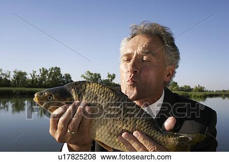 Stock Photo - Businessman holding a fish.. Fotosearch