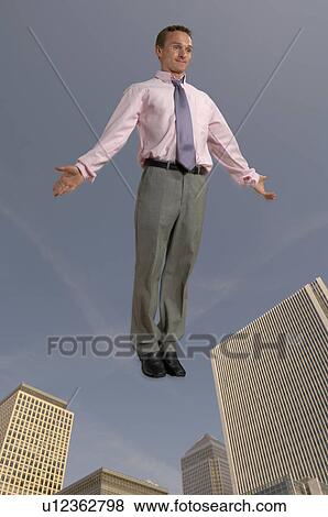Stock Photo - Businessman in the air with city in the background. Fotosearch