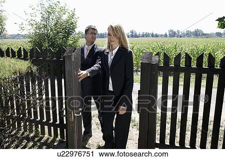 Stock Image - Businessman opening gate for businesswoman.. Fotosearch