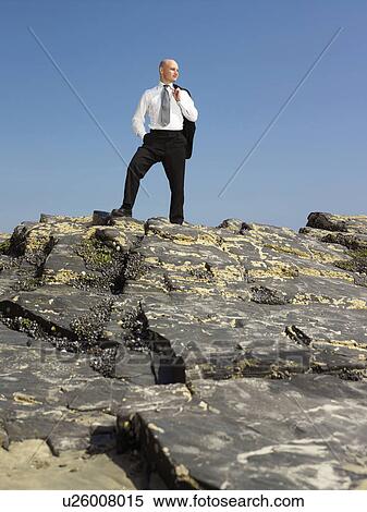 Stock Photography - Businessman standing on rock.. Fotosearch