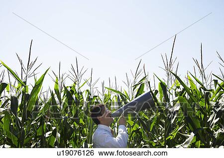 Stock Photograph - Businessman with megaphone in cornfield.. Fotosearch