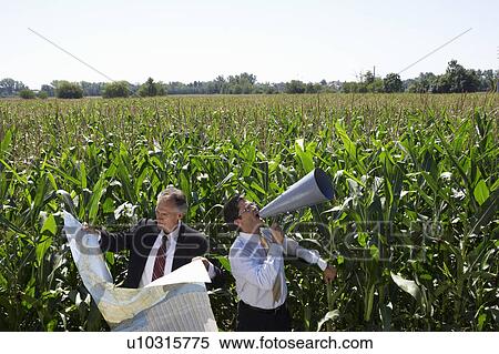 Stock Photography - Businessmen in a cornfield with a map and megaphone.. Fotosearch