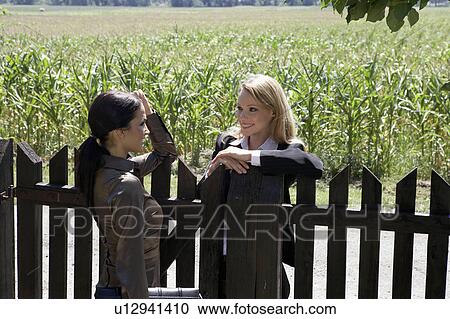 Two businesswomen talking over wooden fence. View Large Photo Image Stock Image - Two businesswomen talking over wooden fence.. Fotosearch