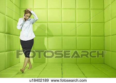 Stock Photo - Woman talking on phone in green padded cell. Fotosearch