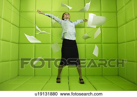 Stock Image - Woman throwing papers around green padded cell. Fotosearch