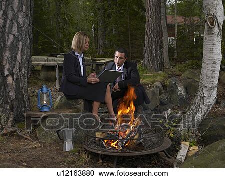 Stock Image - Business meeting by a camp fire. Fotosearch