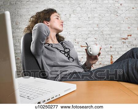 Businesswoman having break, resting feet on desk, eyes closed View Large Photo Image Stock Photo - Businesswoman having break, resting feet on desk, eyes closed. Fotosearch