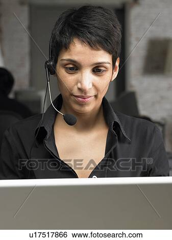 Businesswoman wearing headset, working on laptop. Brussels, Belgium. View Large Photo Image Stock Photograph - Businesswoman wearing headset, working on laptop. Brussels, Belgium.. Fotosearch