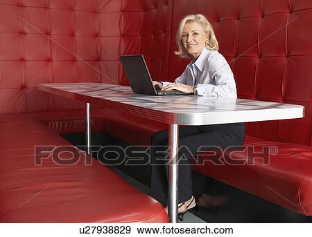 Businesswoman working at a table with red seating View Large Photo Image Stock Photo - Businesswoman working at a table with red seating. Fotosearch