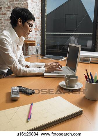 Picture - Businesswoman working on laptop at dusk. Brussels, Belgium.. Fotosearch