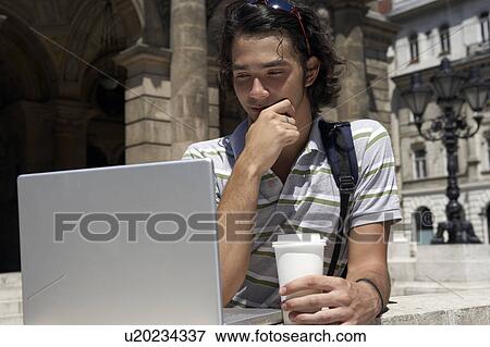 Stock Photo - Man on laptop by the opera house in Hungary.. Fotosearch