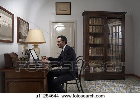 Man using laptop in home office View Large Photo Image Picture - Man using laptop in home office. Fotosearch