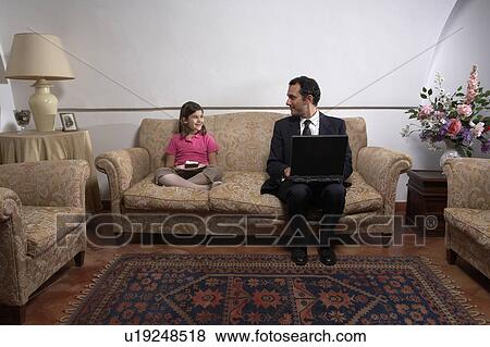 Man using laptop looking at daughter (6-8) on sofa with cake View Large Photo Image Stock Photo - Man using laptop looking at daughter (6-8) on sofa with cake. Fotosearch