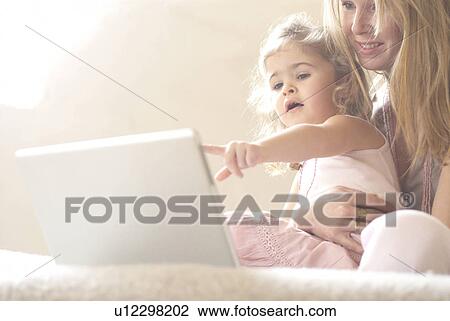 Stock Image - Mother and daughter (2-4) using laptop.. Fotosearch