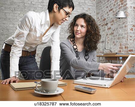 Two businesswomen working on a laptop., Brussels, Belgium. View Large Photo Image Stock Photo - Two businesswomen working on a laptop., Brussels, Belgium.. Fotosearch