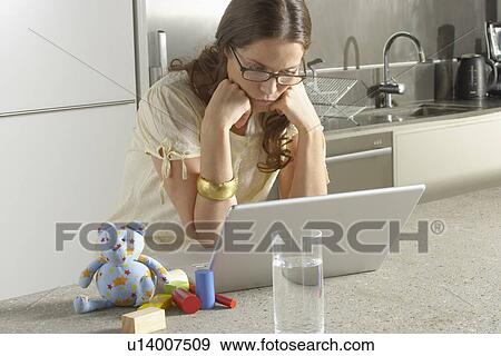 Stock Photo - Young business woman working from home kitchen.. Fotosearch