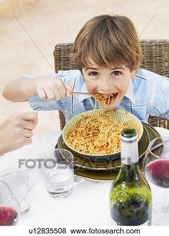 Boy (4-6) eating spaghetti, smiling, portrait View Large Photo Image Stock Photo - Boy (4-6) eating spaghetti, smiling, portrait. Fotosearch
