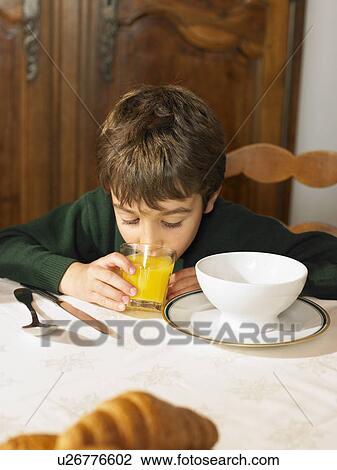 Boy (6-8) drinking orange juice at breakfast View Large Photo Image Stock Image - Boy (6-8) drinking orange juice at breakfast. Fotosearch