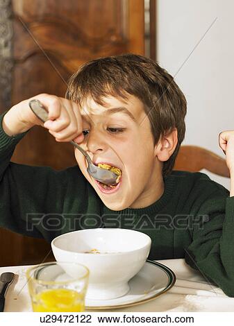 Boy (6-8) eating cereal at breakfast View Large Photo Image Stock Image - Boy (6-8) eating cereal at breakfast. Fotosearch