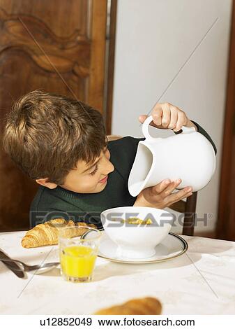 Boy (6-8) looking in milk jug at breakfast View Large Photo Image Stock Photo - Boy (6-8) looking in milk jug at breakfast. Fotosearch
