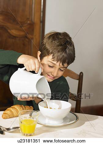 Boy (6-8) pouring milk over cereal at breakfast View Large Photo Image Stock Image - Boy (6-8) pouring milk over cereal at breakfast. Fotosearch