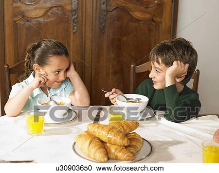Brother (6-8) and sister (4-6) eating cereal at breakfast table View Large Photo Image Stock Image - Brother (6-8) and sister (4-6) eating cereal at breakfast table. Fotosearch