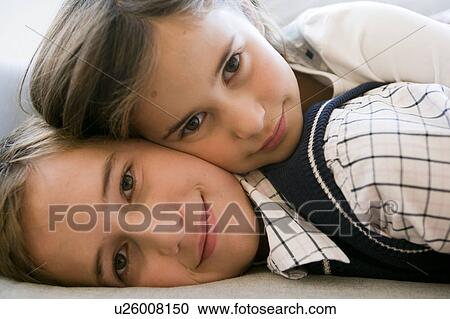 Stock Image - brother and sister lying on sofa. Fotosearch