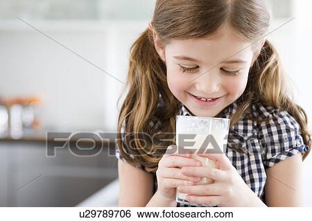 Girl looking into a glass of milk View Large Photo Image Stock Photograph - Girl looking into a glass of milk. Fotosearch