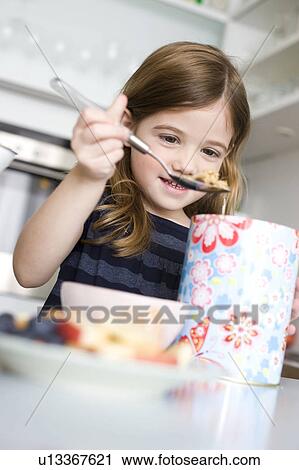 Stock Image - Girl putting cereals into her bowl. Fotosearch