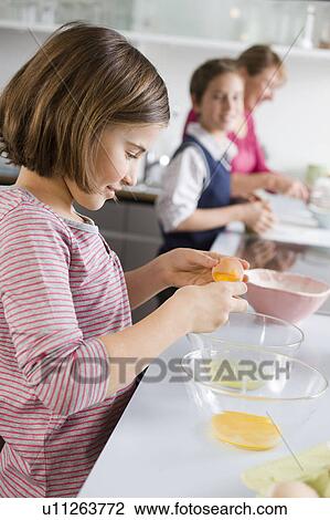 Stock Image - Girl separating egg yolk and egg white. Fotosearch