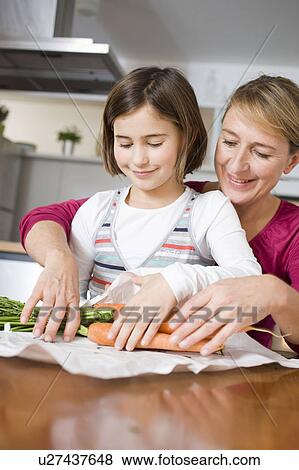 Stock Photo - Mother and daughter preparing carrots. Fotosearch