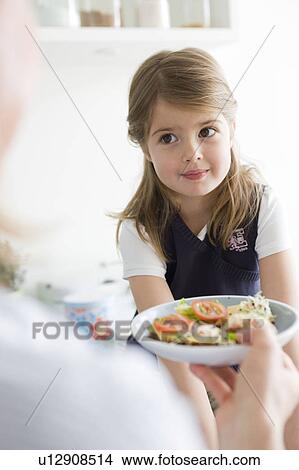 Mother handing plate to daughter View Large Photo Image Picture - Mother handing plate to daughter. Fotosearch