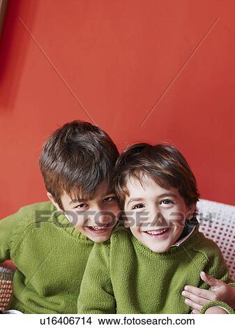 Picture - Two brothers (5-7) sitting together smiling, portrait. Fotosearch
