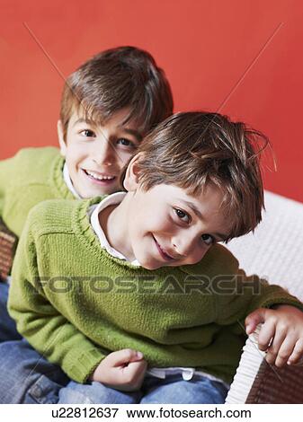 Two brothers (5-7) sitting together smiling, portrait View Large Photo Image Stock Photo - Two brothers (5-7) sitting together smiling, portrait. Fotosearch