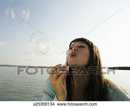 Girl blowing bubbles by lake. View Large Photo Image Picture - Girl blowing bubbles by lake.. Fotosearch
