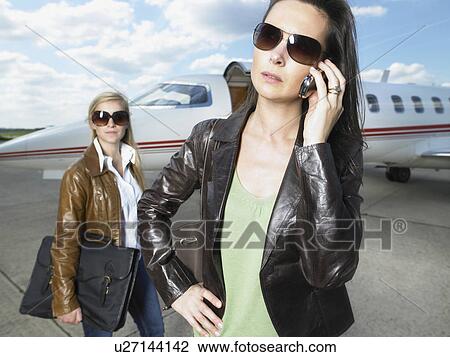 Two businesswomen standing beside private jet. View Large Photo Image Stock Image - Two businesswomen standing beside private jet.. Fotosearch