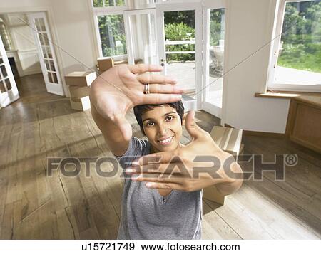 Stock Photo - Woman framing face with hands moving into empty house.. Fotosearch