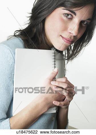 Stock Image - Woman holding notebook to chest.. Fotosearch